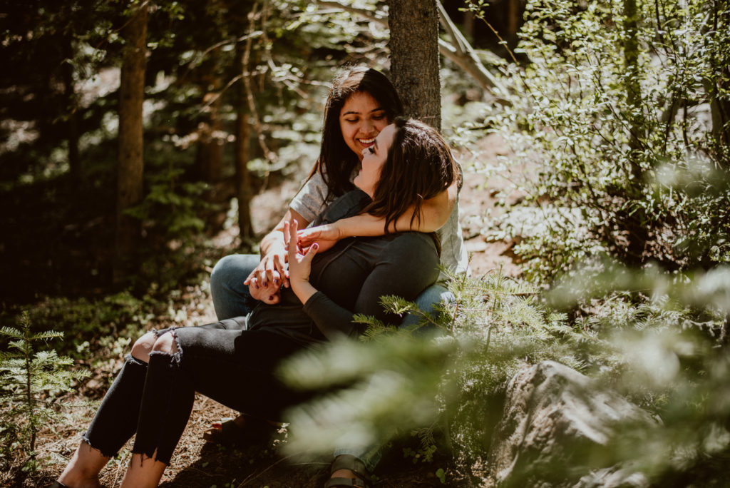 A couple sits together under a tree with their arms around each other. Read on to find out the top 3 tips for a kickass photoshoot!