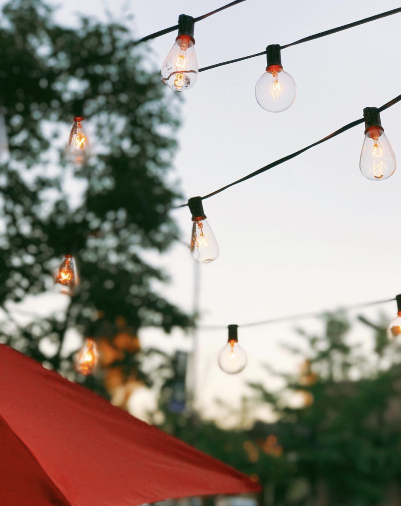 Hanging cafe lights at twilight. Read this post for tips about how to downsize into a tiny home!