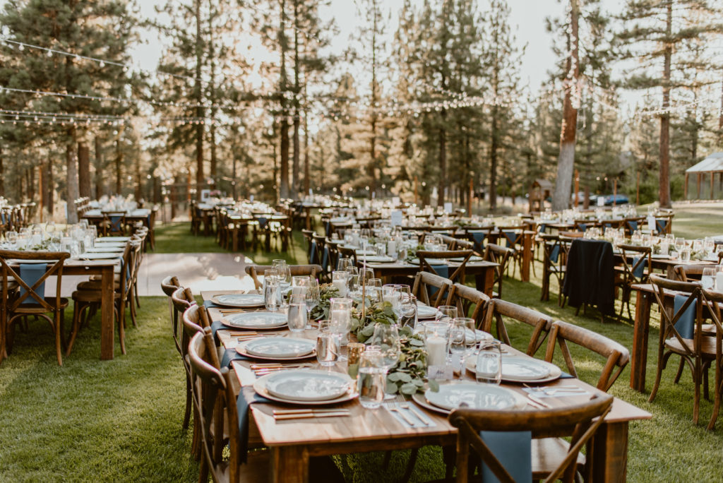 Tables are assembled in the forest at sunset for a wedding reception. Check out this guide for the best ways to figure out how much wedding photography coverage you need!