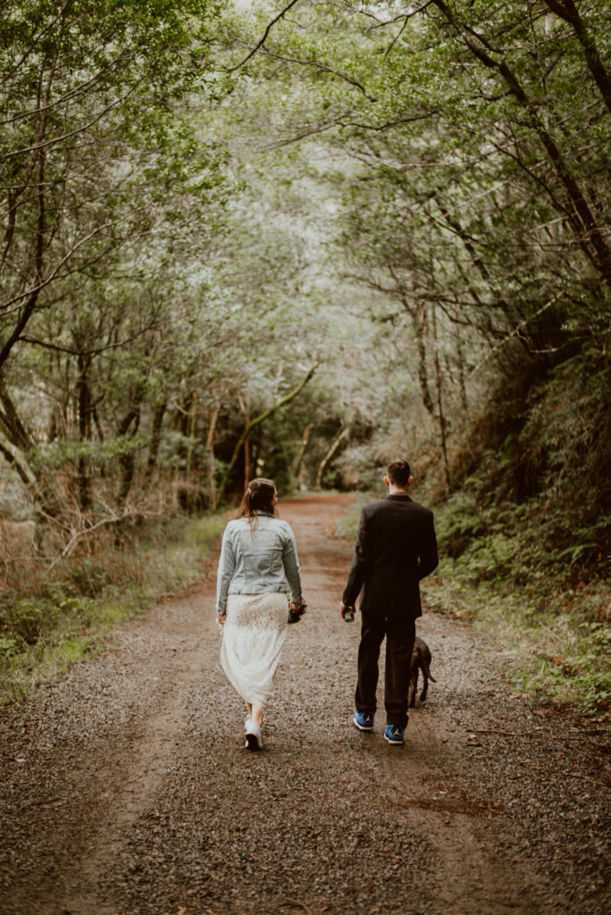 A bride and groom walk along a path in the forest with their dog. Head to this post for more photos from their day-after wedding session!