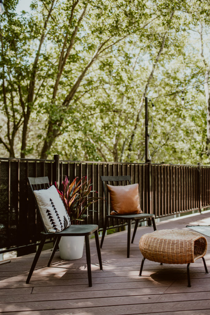 Two chairs and a footstool are ready for guests on a deck. A backyard deck is given a summer refresh.