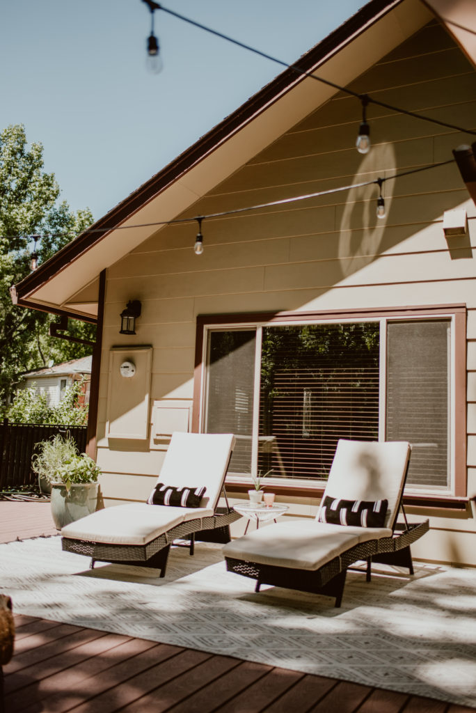 Two chaise lounge chairs lie waiting in the sun. A backyard deck is given a summer refresh.