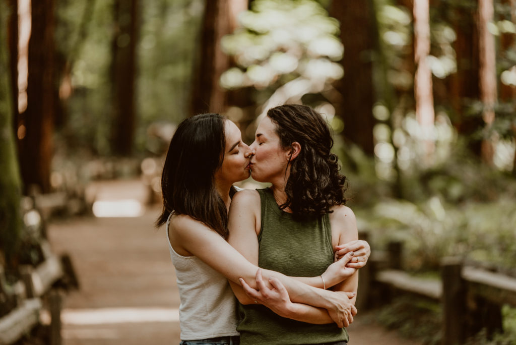 Two women embrace with their arms around each other. Be sure to check out this post for photos from their forest and river engagement session!