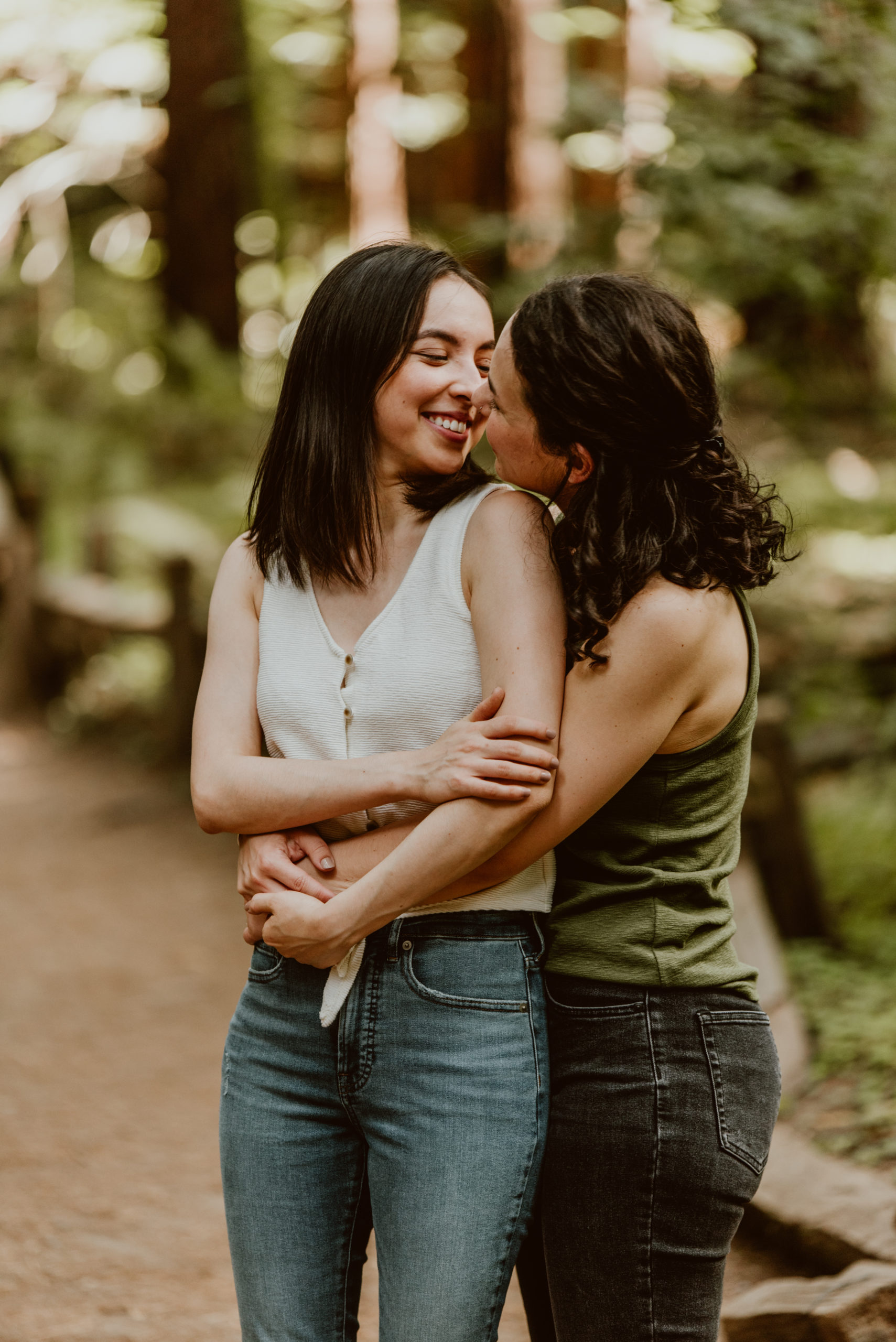 Two women embrace with their arms around each other. Be sure to check out this post for photos from their forest and river engagement session!