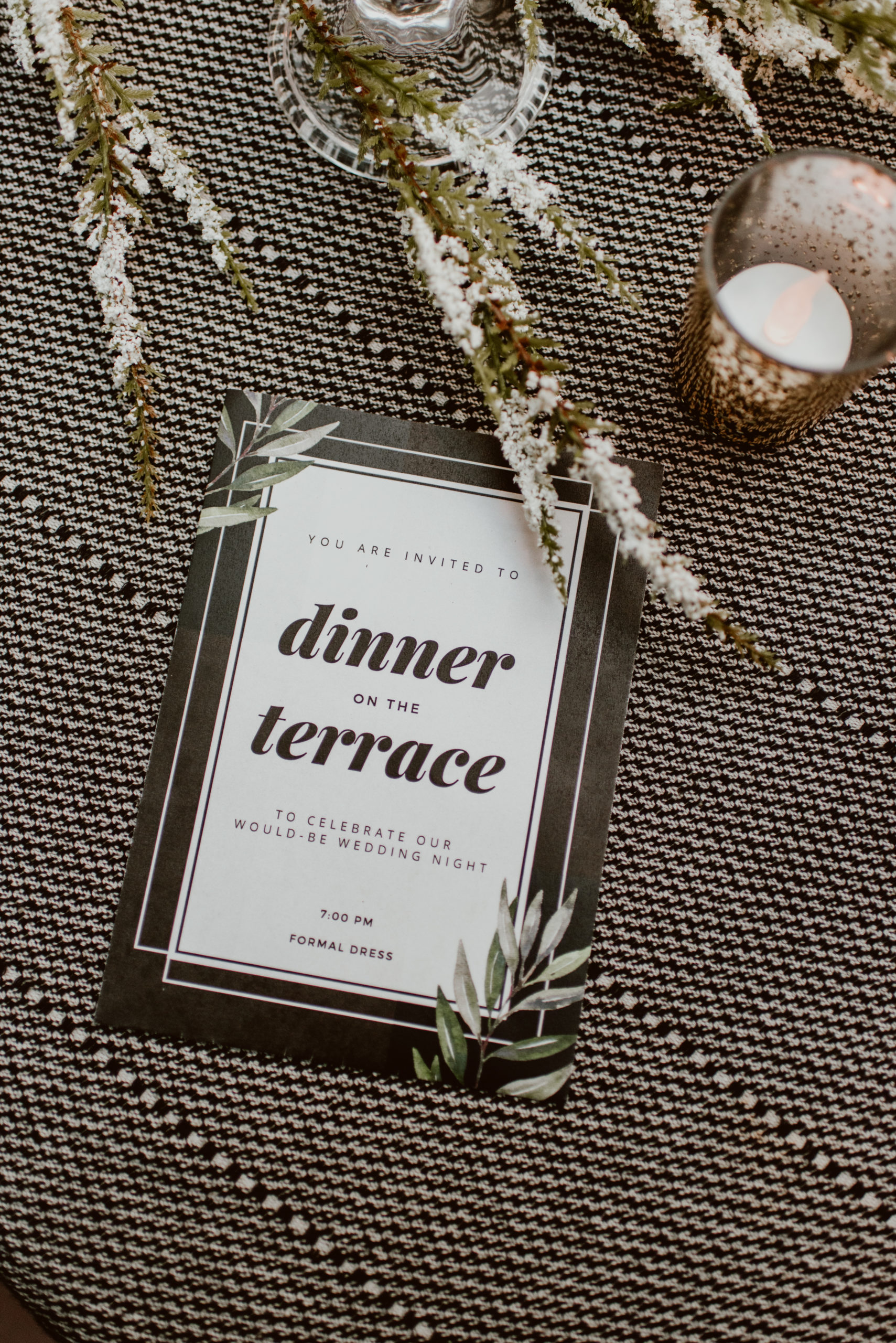 A dinner invitation rests on a table next to a candle. Read this post for an elegant and easy way to celebrate your original wedding date.