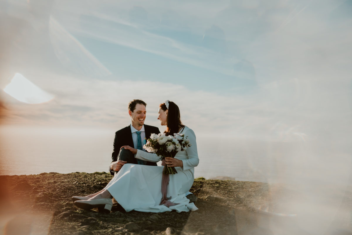 "You're being so selfish!" The words none of us want to hear about our wedding days. But are elopements actually selfish? Click to find out!

A bride and groom sit on top pf a hill overlooking the Pacific Ocean in California on their elopement day.