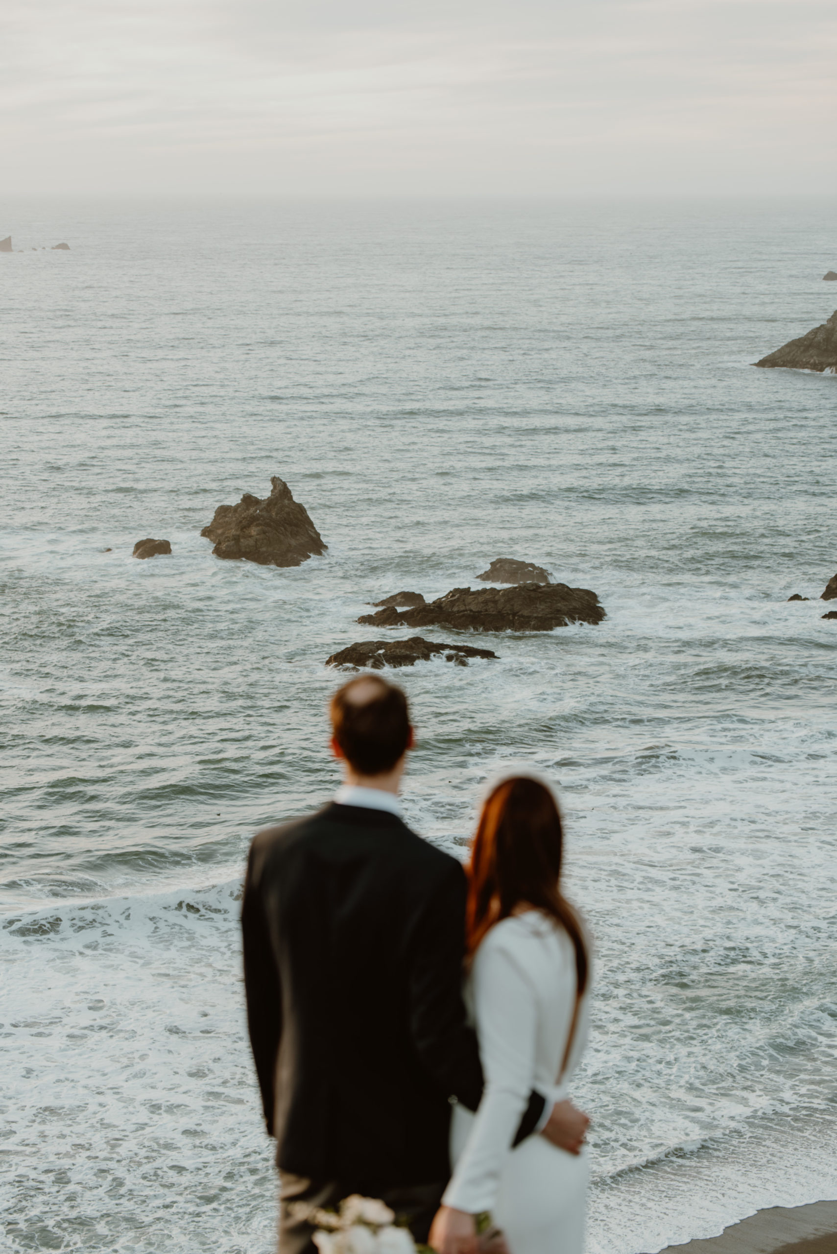 "You're being so selfish!" The words none of us want to hear about our wedding days. But are elopements actually selfish? Click to find out!

A bride and groom stand arm-in-arm on top pf a cliff overlooking the Pacific Ocean in California on their elopement day.