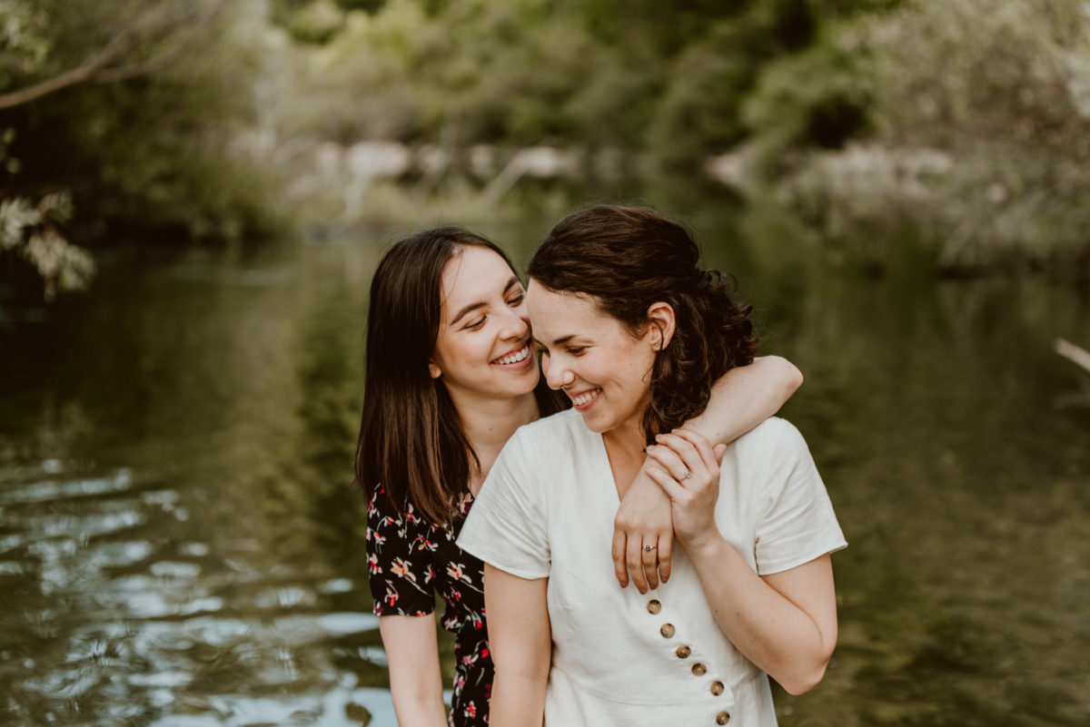 Two women stand back-to-front in the middle of a creek. One has her arm around the other and they share a smile together.

Head to this post to learn the three things you need to choose your session location!