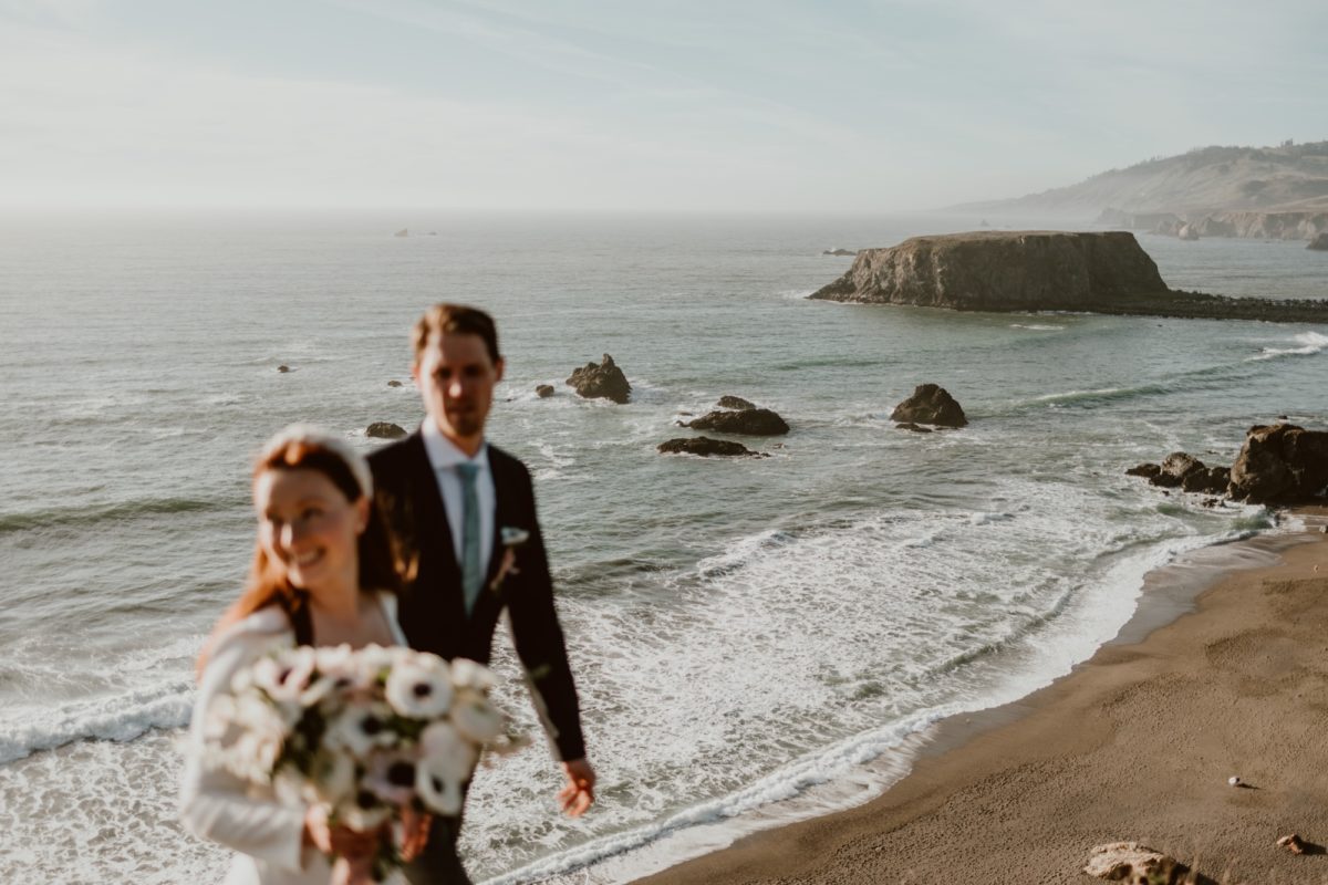 A couple walk hand in hand on their elopement day on the Sonoma coast.