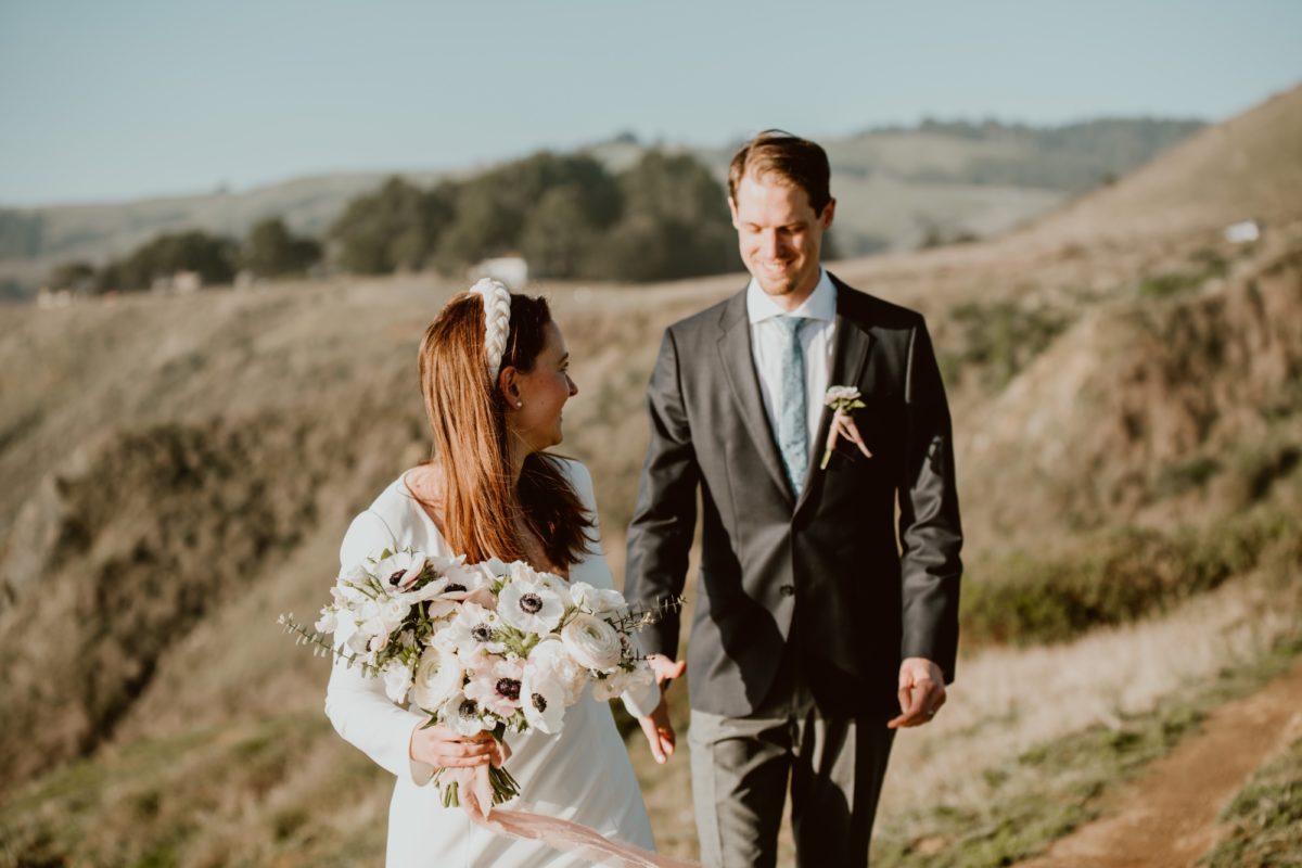 A couple walk hand in hand on their elopement day on the Sonoma coast.