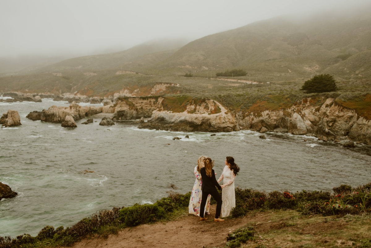 Two women stand holding hands on the edge of the coastline during their elopement ceremony. Feeling stuck in a box with your wedding planning? Here are my 7 hot takes on wedding traditions to break you out of a planning rut.