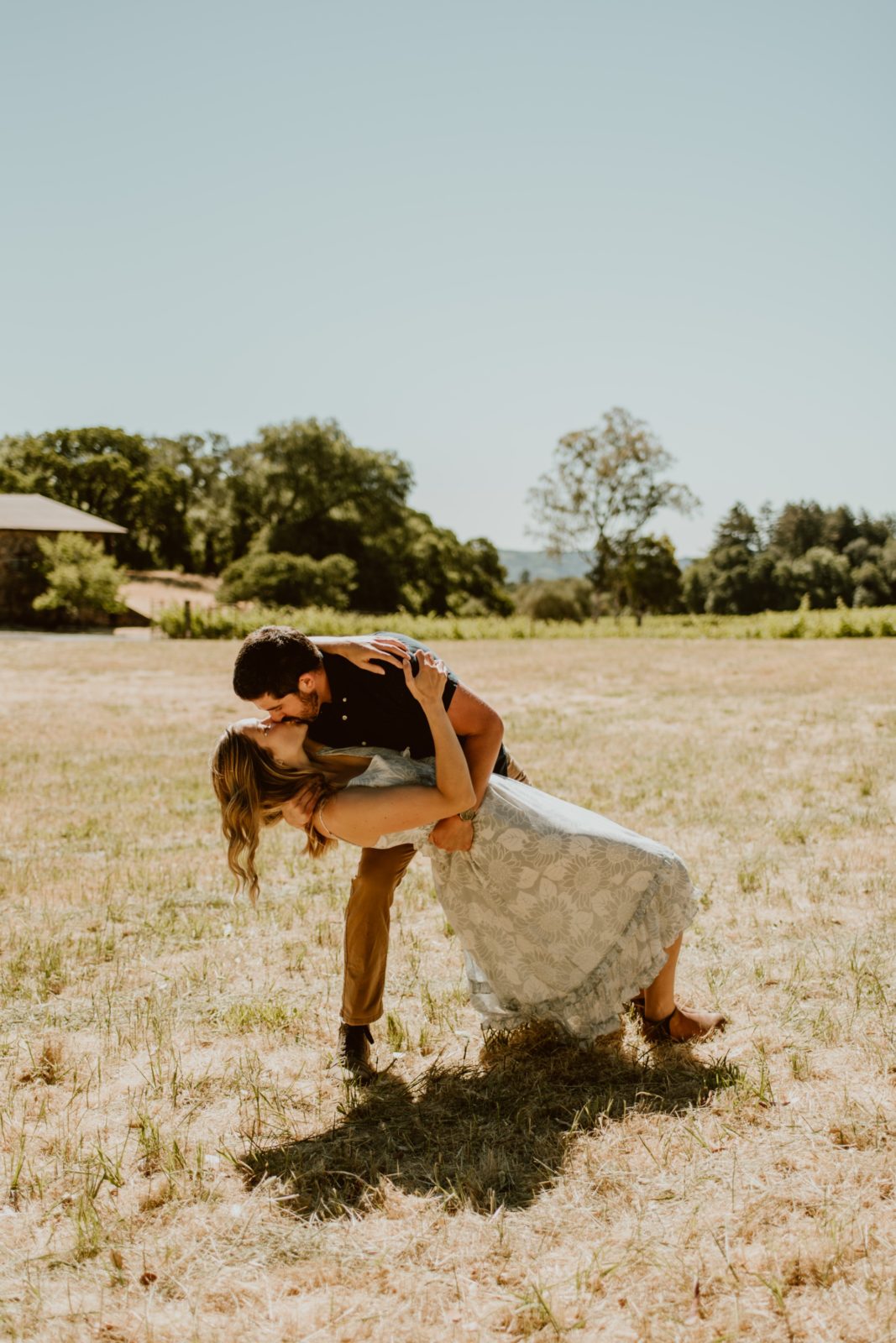 A man dips his fiancé for a kiss in Jack London State Park for their engagement session.